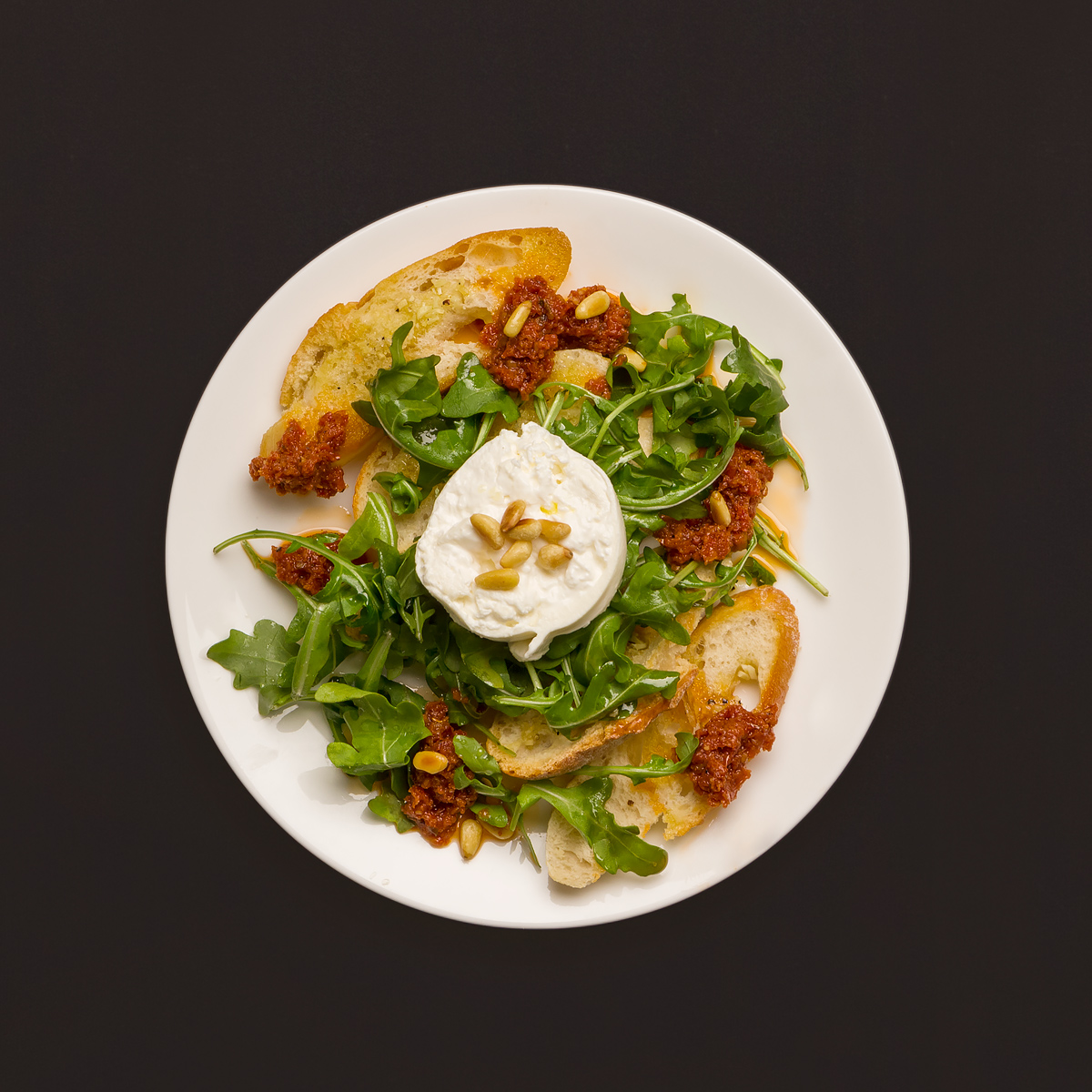 Italienischer Burrata auf Rucolasalat mit Pesto Rosso und Knoblauch ...